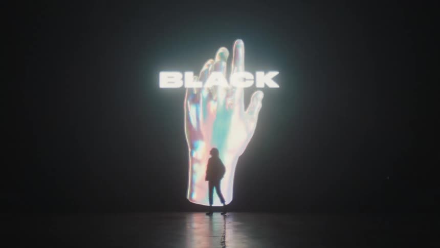 A woman walks back and forth on a stage in front of a large digital display for black friday