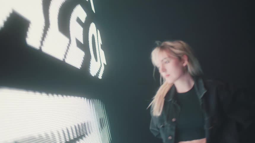 Silhouette of a woman modeling in front of a black friday digital display on the wall of a smoky dark room