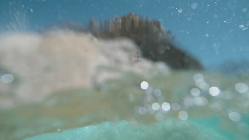 Ocean waves crashing on the coastline of a beach near a promontory at daytime