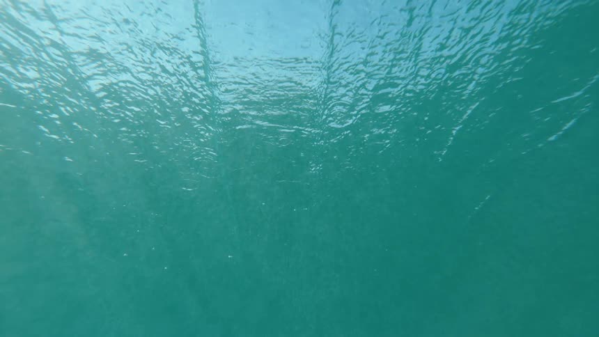 Underwater view of sunlight shining in the rippling blue water