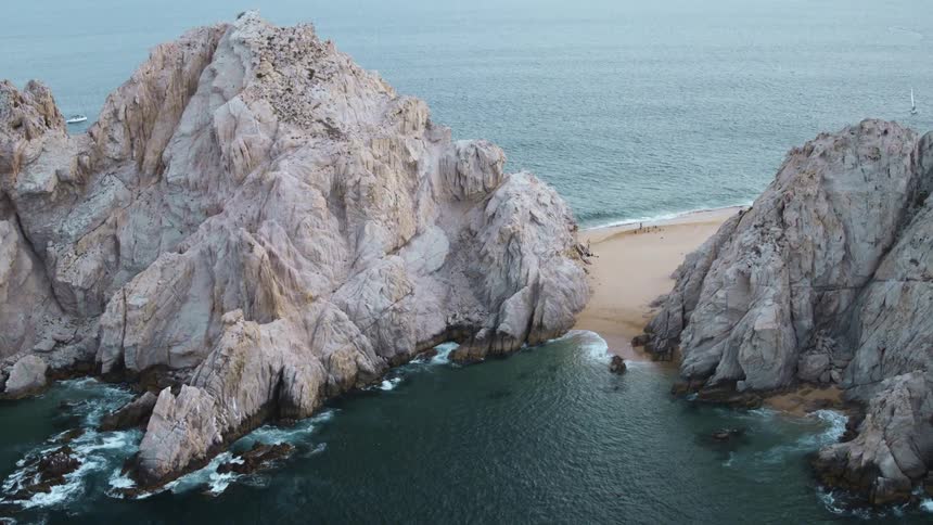 A sandy beach below large rock formations on a sunny day