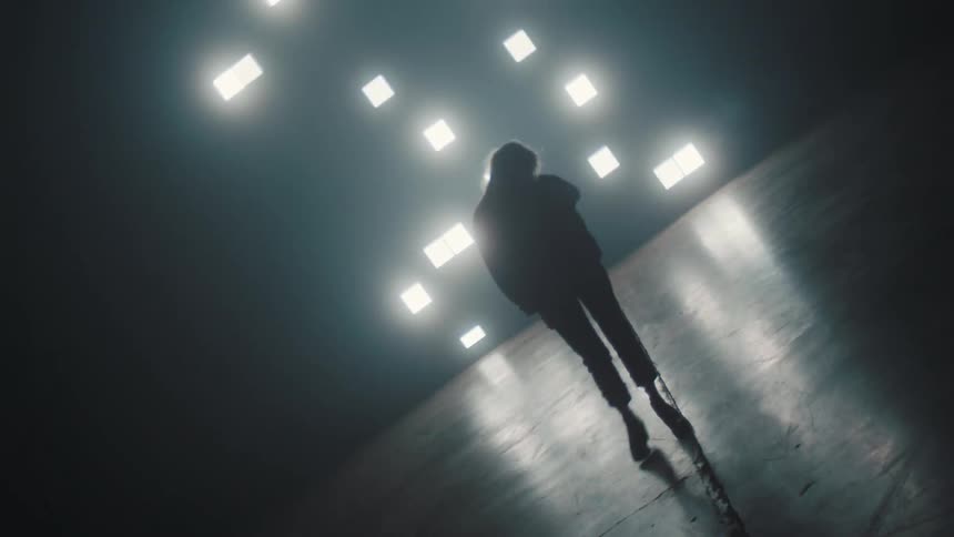 Silhouette of a woman walking from side to side in front of a display of square flashing lights twinkling around