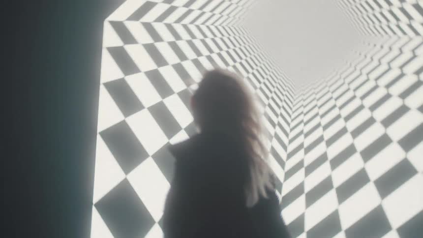 Silhouette of a woman dancing in front of the checkered pattern inside a giant display