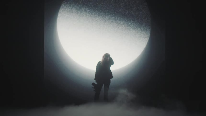 A silhouette of a woman holding a camera on a stage with smoke with a big screen in the background