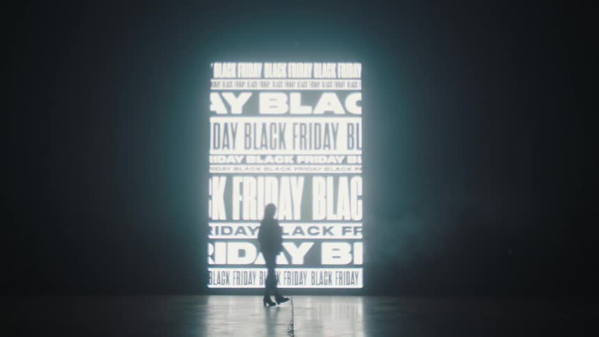 A silhouetted woman walking in front of projected text on a wall