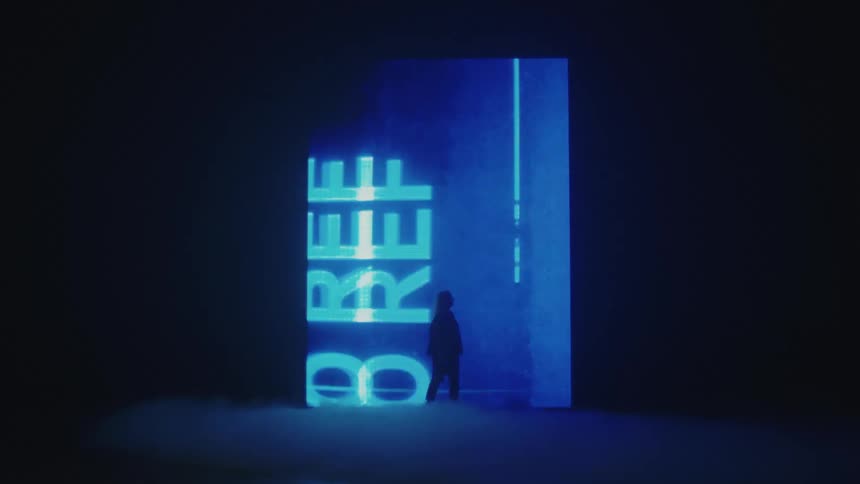 Silhouette of a woman modeling in front of LED sign projected on the wall of a smoky dark room