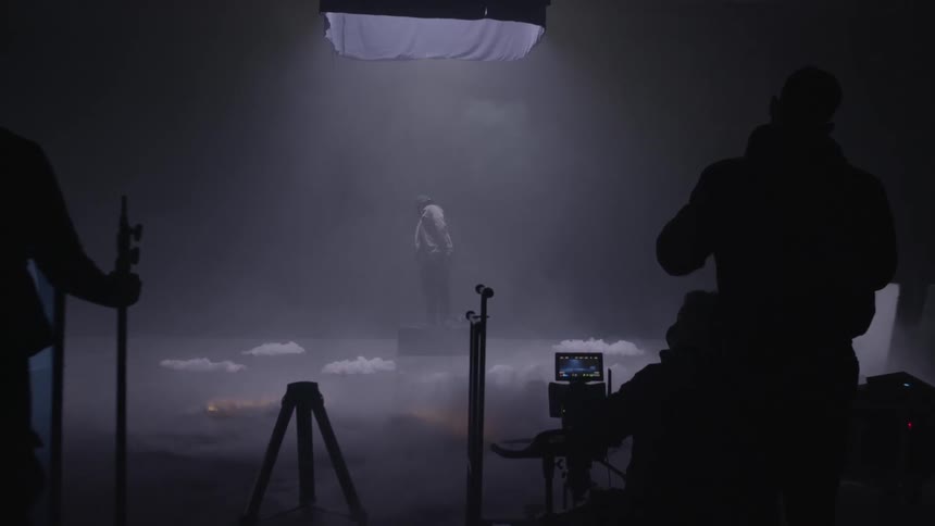 Crew looks on as person stands under lights on set