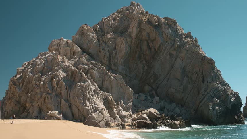 Coastal rock formation along beach shoreline on a clear day