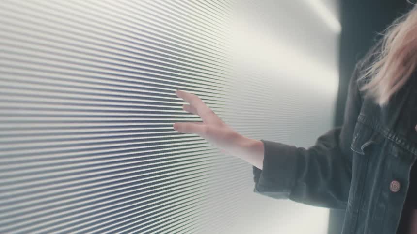 Silhouette of a woman modeling in front of a digital screen projected on the wall of a smoky dark room