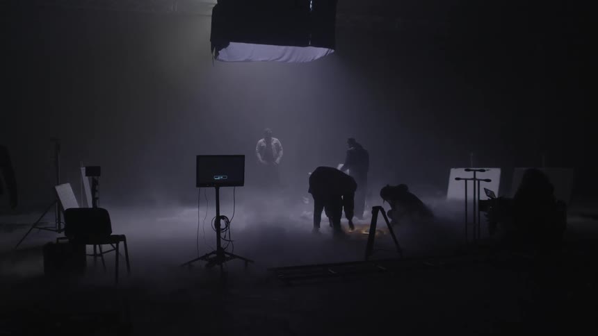 Silhouette of people working on a stage with smoke