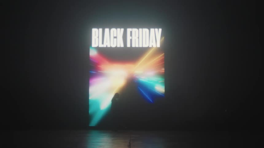 Silhouette of a woman modeling in front of a colorful black friday sign projected on the wall of a smoky dark room