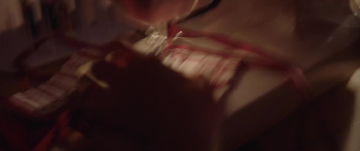 A pair of hands using a sewing machine to sew a red and white face mask together