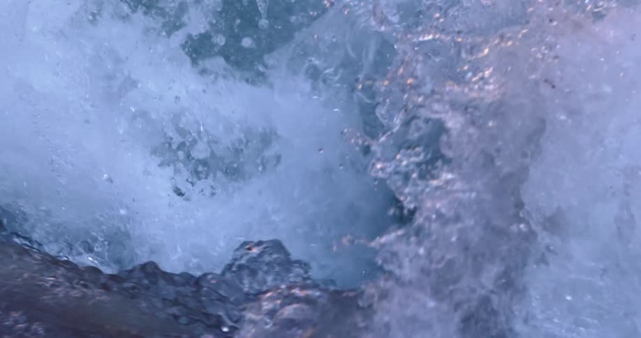 Beautifully colored leaping water as the camera looks down a raging whitewater rapid deep in Grand Canyon National Park along the Colorado River at sunset in slow motion