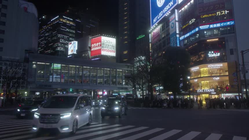 Vehicles driving over the zebra crossing on an intersection in the citys downtown streets at night