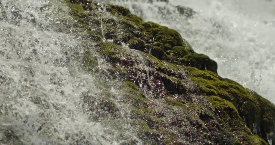 Slow motion shot of a waterfall cascading down a moss covered cliff face deeep in the Gran Canyon