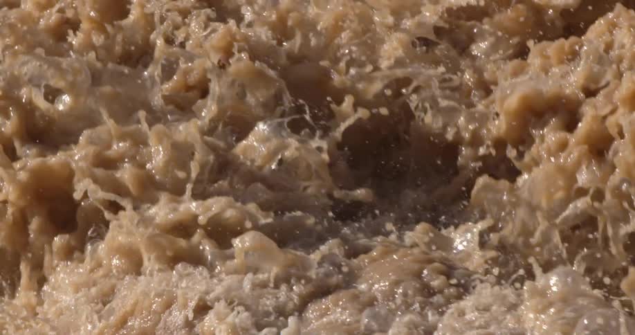 Tight slow motion shot of sediment heavy brown muddy water of the Colorado River deep within Grand Canyon National Park