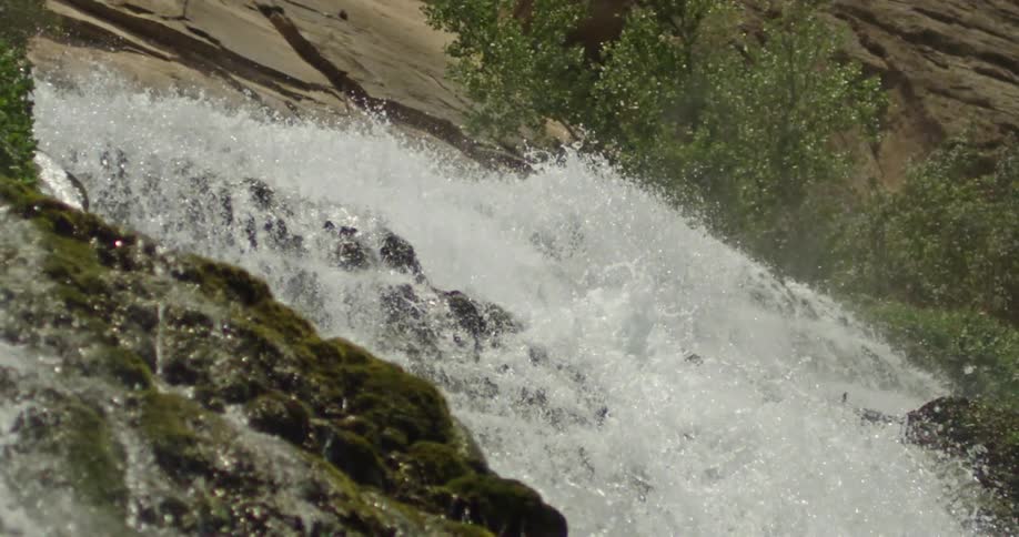 Slow motion lookup shot of a cascading waterfall deep in the arid wilderness of Grand Canyon National Park in Arizona on the Colorado River