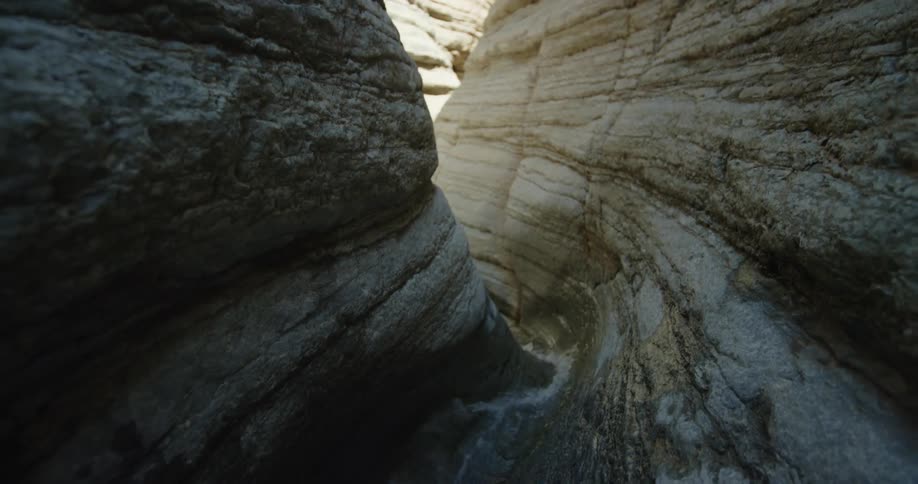 The camera lifts from water level revealing a striated and narrow slot canyon deep in Grand Canyon National Park in Arizona
