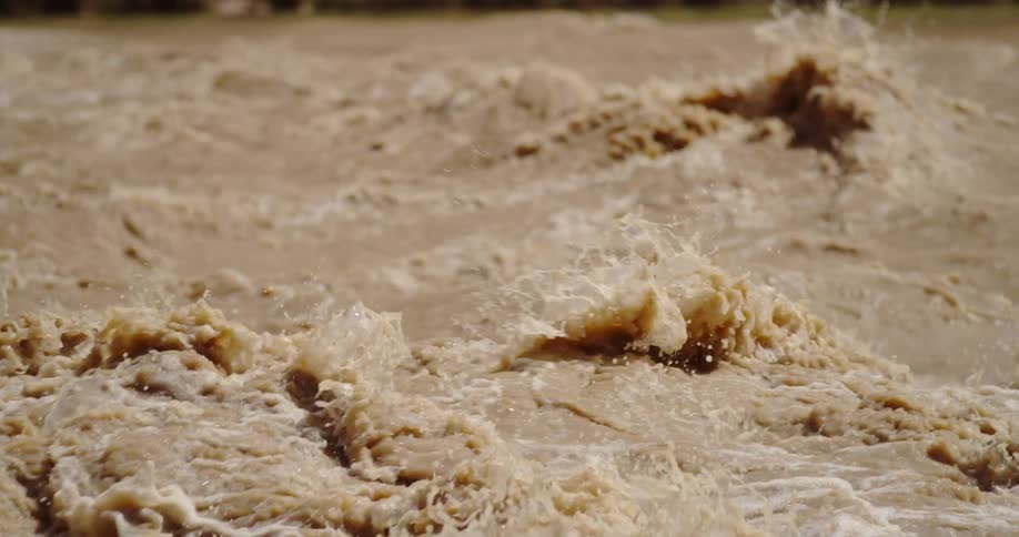 Slow motion shot of muddy churning Colorado River water crashing down whitewater rapids deep in the Colorado River Grand Canyon corridor in Grand Canyon National Park