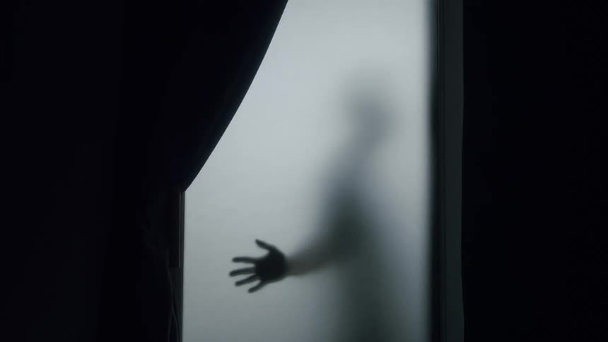 A person on another side of a glass slides their hand across and walks away