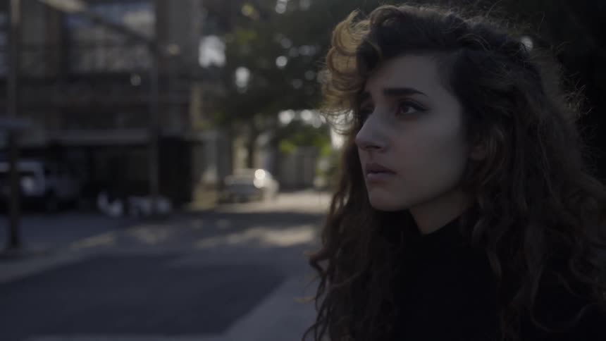 A woman looks sad as she stands outside