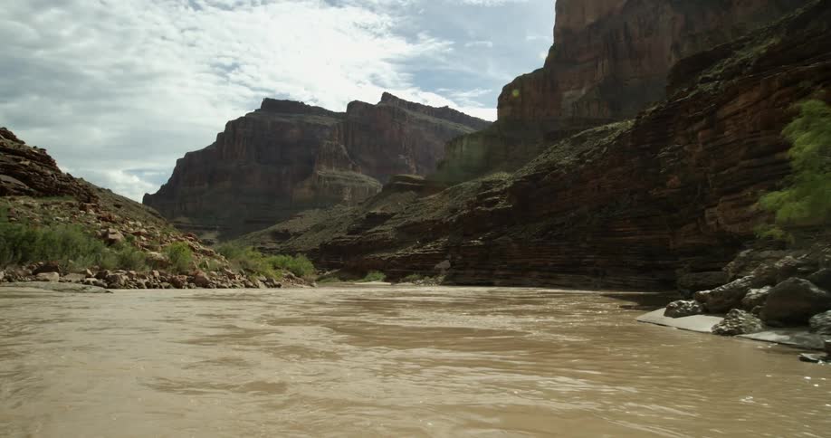 POV shot from a whitewater raft deep in the Grand Canyon National Park on the Colorado River during the muddy monsoon season with a cloudy sky