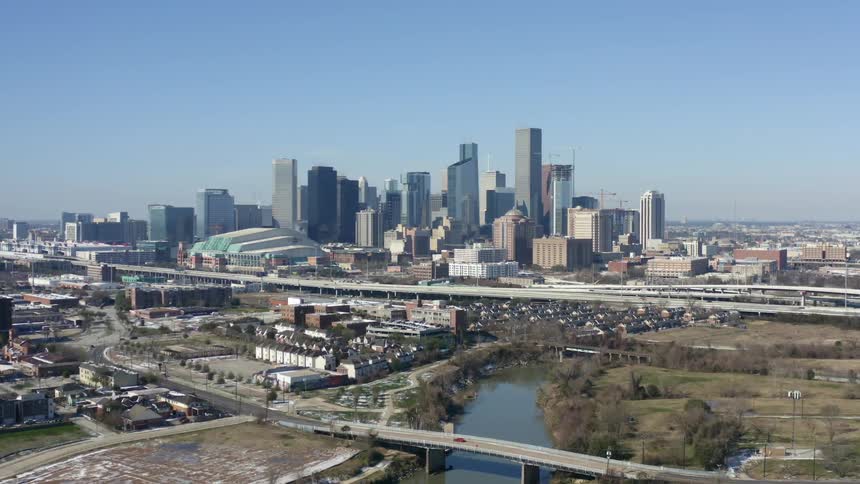 Bridge covers river winding toward slightly hazy downtown skyline