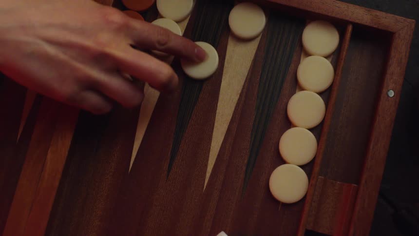 Close up of womans hand moving circular pieces in backgammon