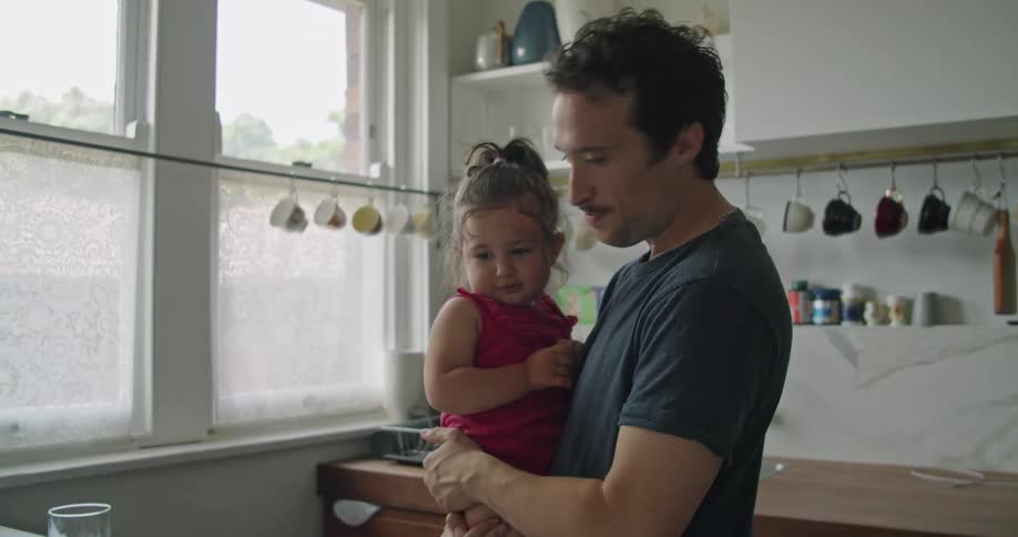 A father holding his daughter in a kitchen