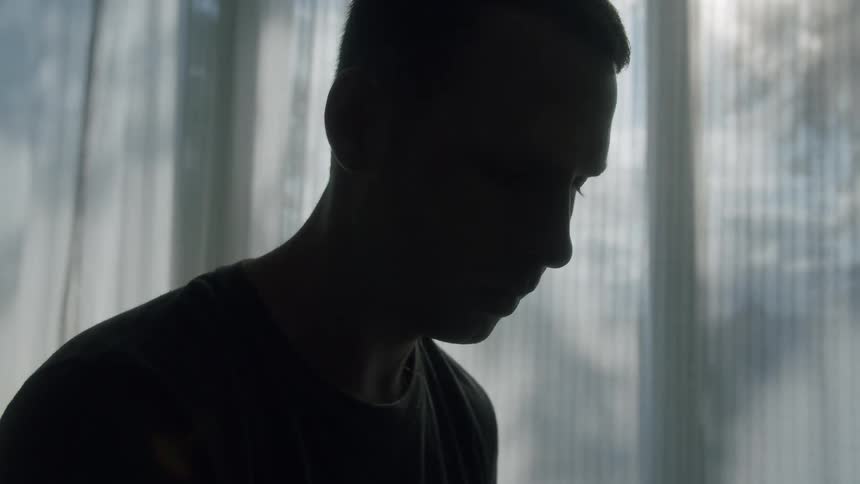 Man stands near window curtains with filmy fabric