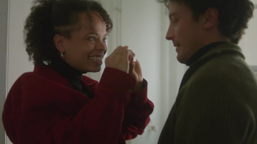 Wife hugs her husband then shows him the results of a pregnancy test smiles and hugs him again indoors in a home during the day