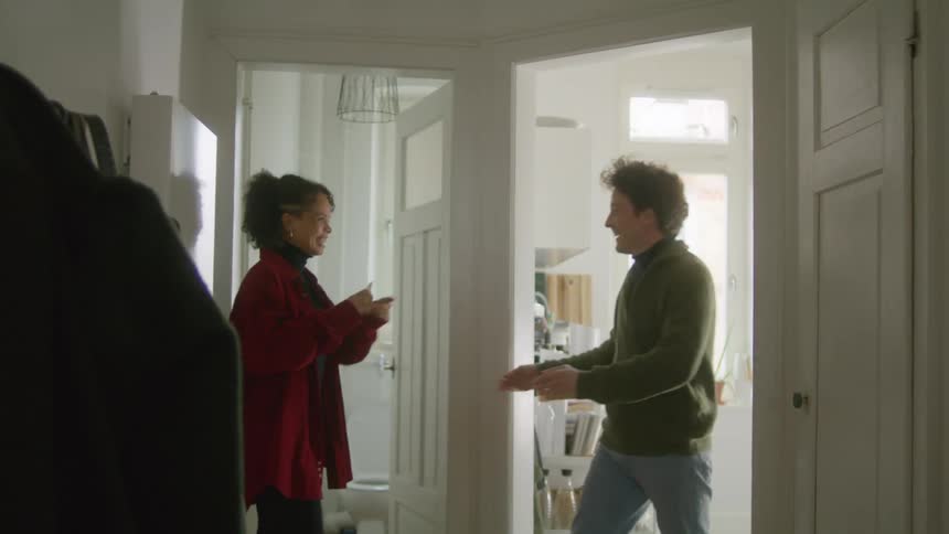 A woman exits the bathroom to give a waiting man the results of her pregnancy test before jumping into his arms in celebration