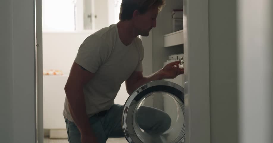 Man placing dirty clothes into a front loader at home