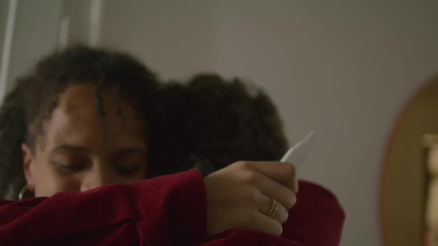 A woman holding a pregnancy test hugs a man
