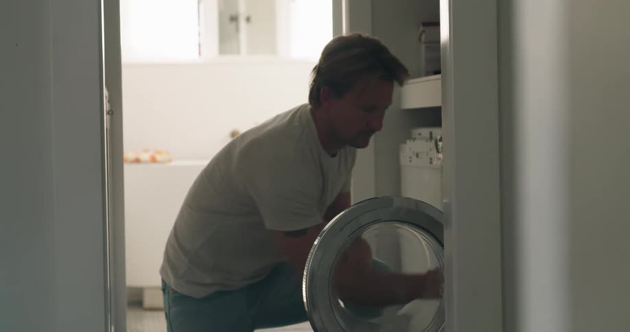 A man is putting laundry in the washing machine