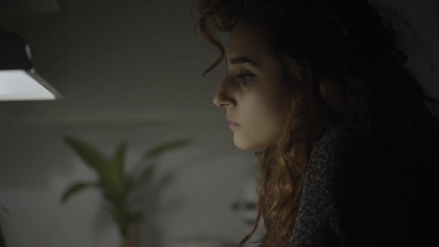 A woman stares with a light shining on her