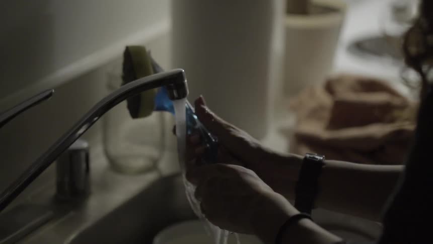 A person washes a dish sponge in the sink of a kitchen