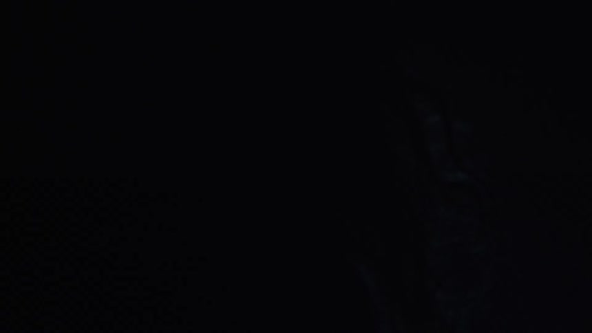 A woman is talking in a dark area with lights flashing