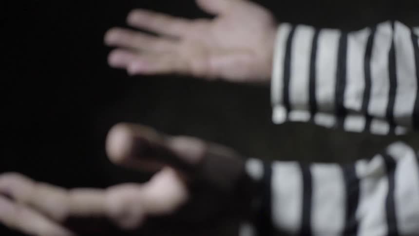 Two hands wearing a pinstripe shirt turn their palms up