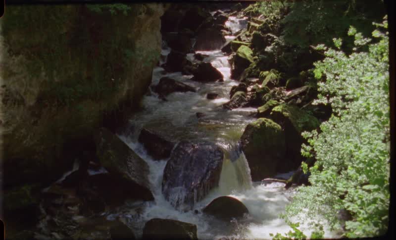 A river and waterfall with rocks with trees the sky and clouds in the background