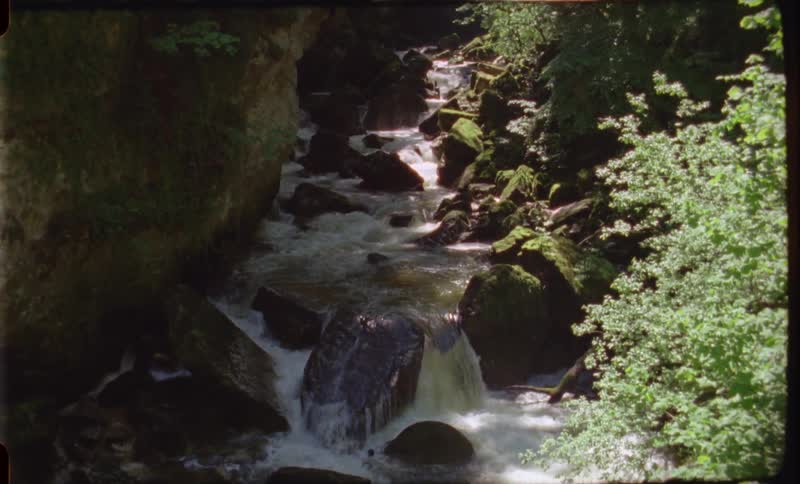 A river filled with large rocks in the wilderness during the day