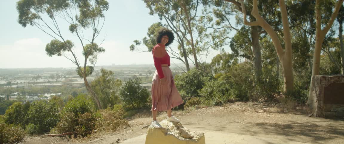 Young woman wearing a long skirt balancing over a rock in a trail on the mountain