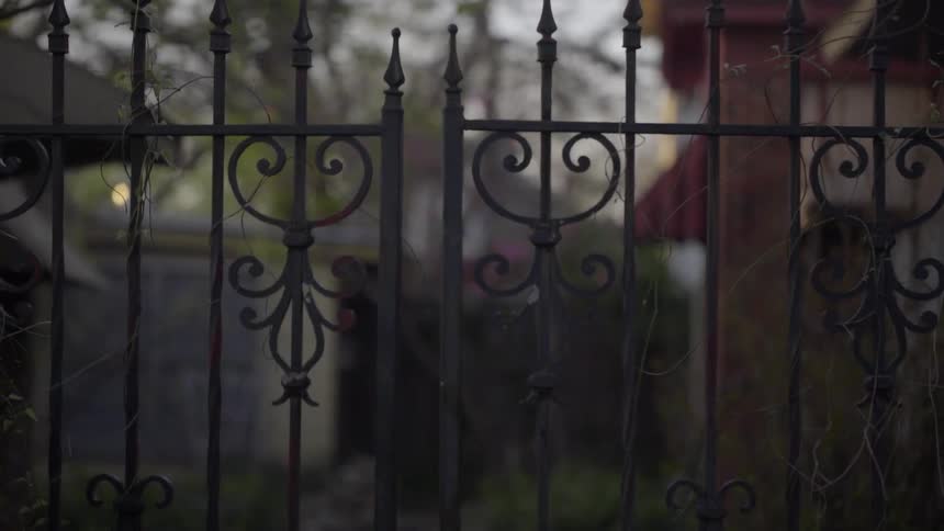 A wrought iron fence stands in front of a cemetery