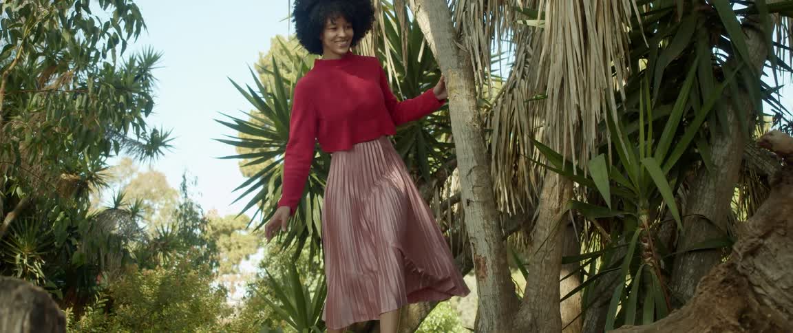 A woman is walking outdoors in a tropical area during the day
