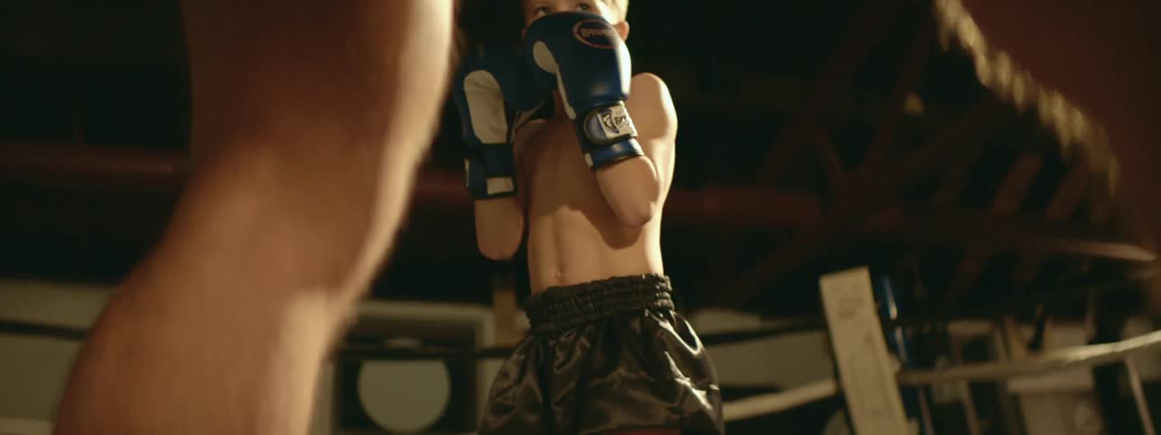 A young boy learning to box in a ring on a gym