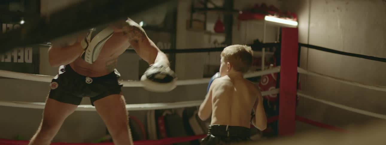 A man is boxing with a child in the ring