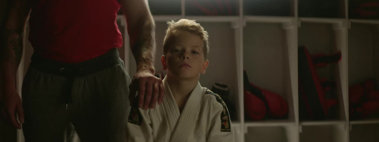 Boy wearing karate uniform sitting in a bench on the locker room