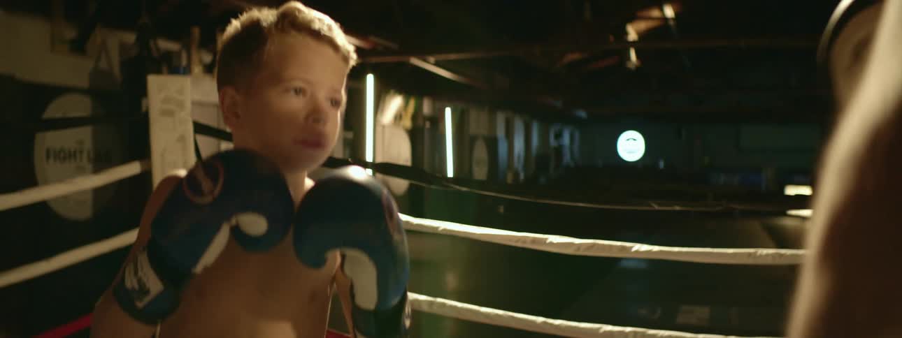 A boy and a man in a gym practicing boxing in a boxing ring