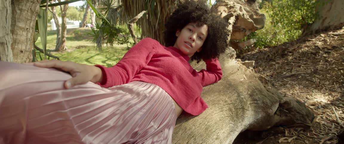 A woman is laying in a forest during the day