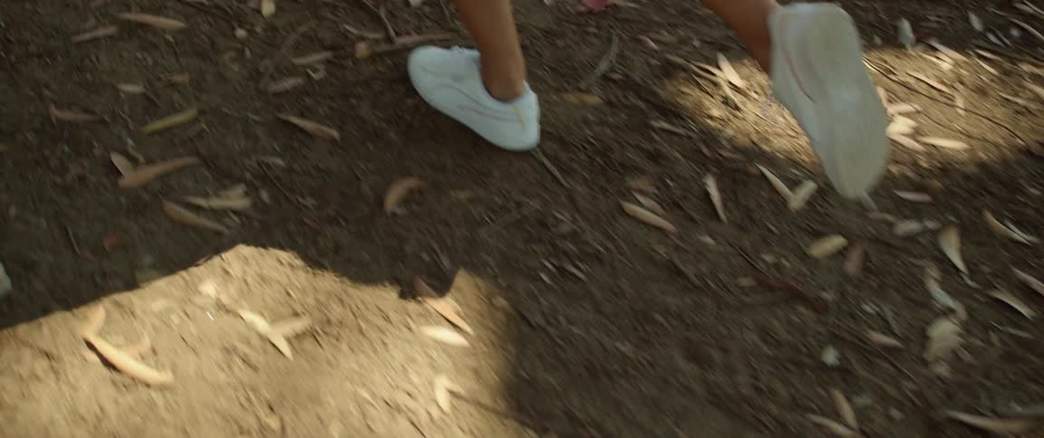 A female in a pink skirt running over dirt ground